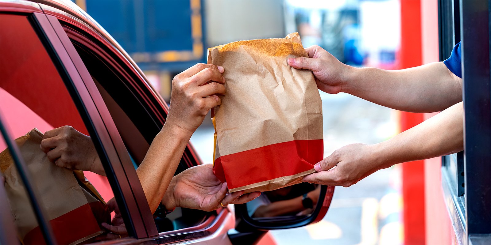 McDonald's drive-thru service with a customer receiving a food order in a paper bag, symbolizing the company's legal victory after obtaining dismissal of BIPA claims through summary judgment.