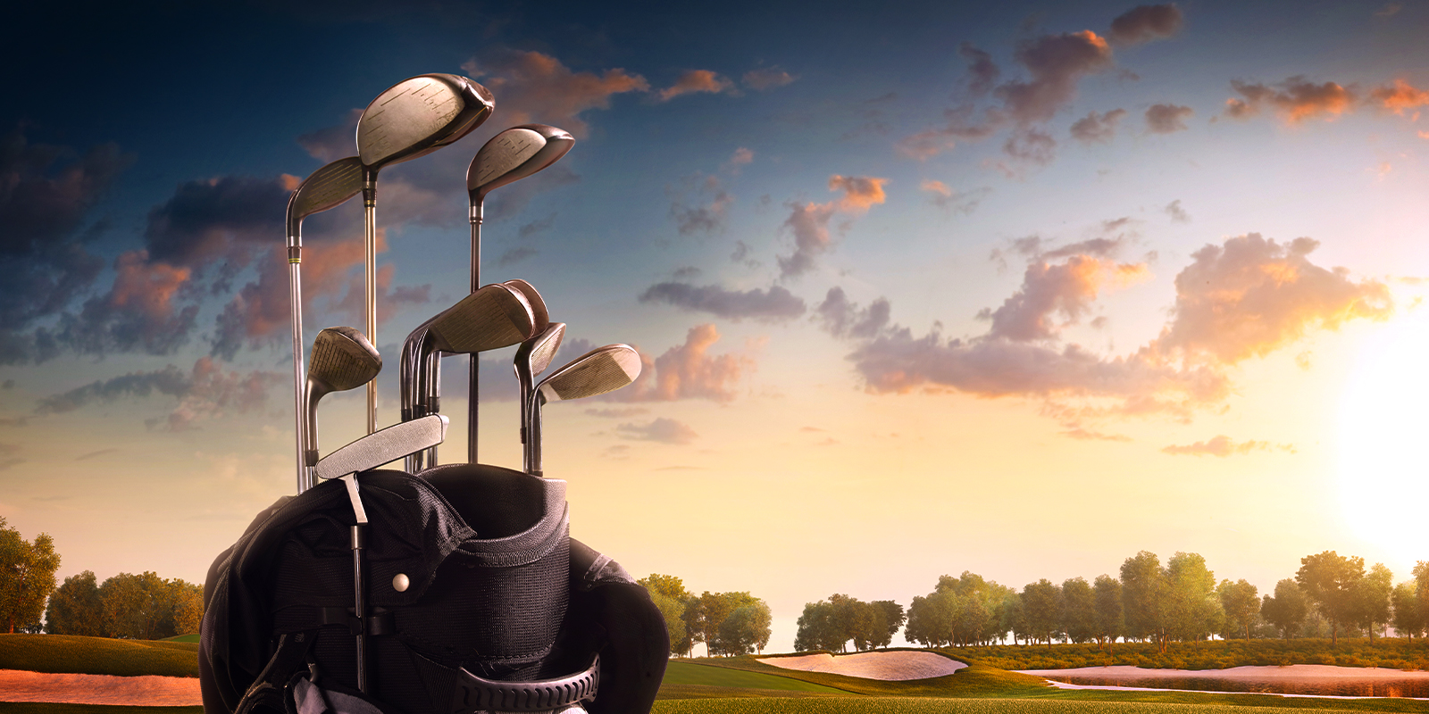 Golf bag with clubs set against a scenic golf course at sunset, featuring a vibrant sky and lush green fairways in the background.