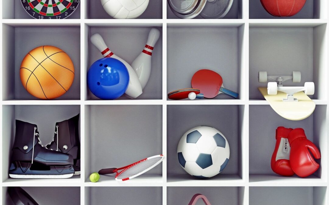 A grid of cubby holes containing various sports equipment including a dartboard, basketball, bowling pins, baseball glove, hockey skates, tennis racket, soccer ball, boxing gloves, and a skateboard.