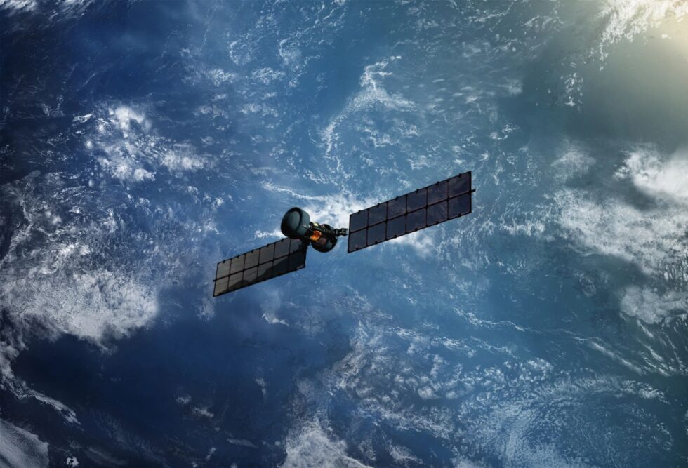 Satellite orbiting Earth with solar panels extended, set against a backdrop of the planet's blue atmosphere and scattered clouds.